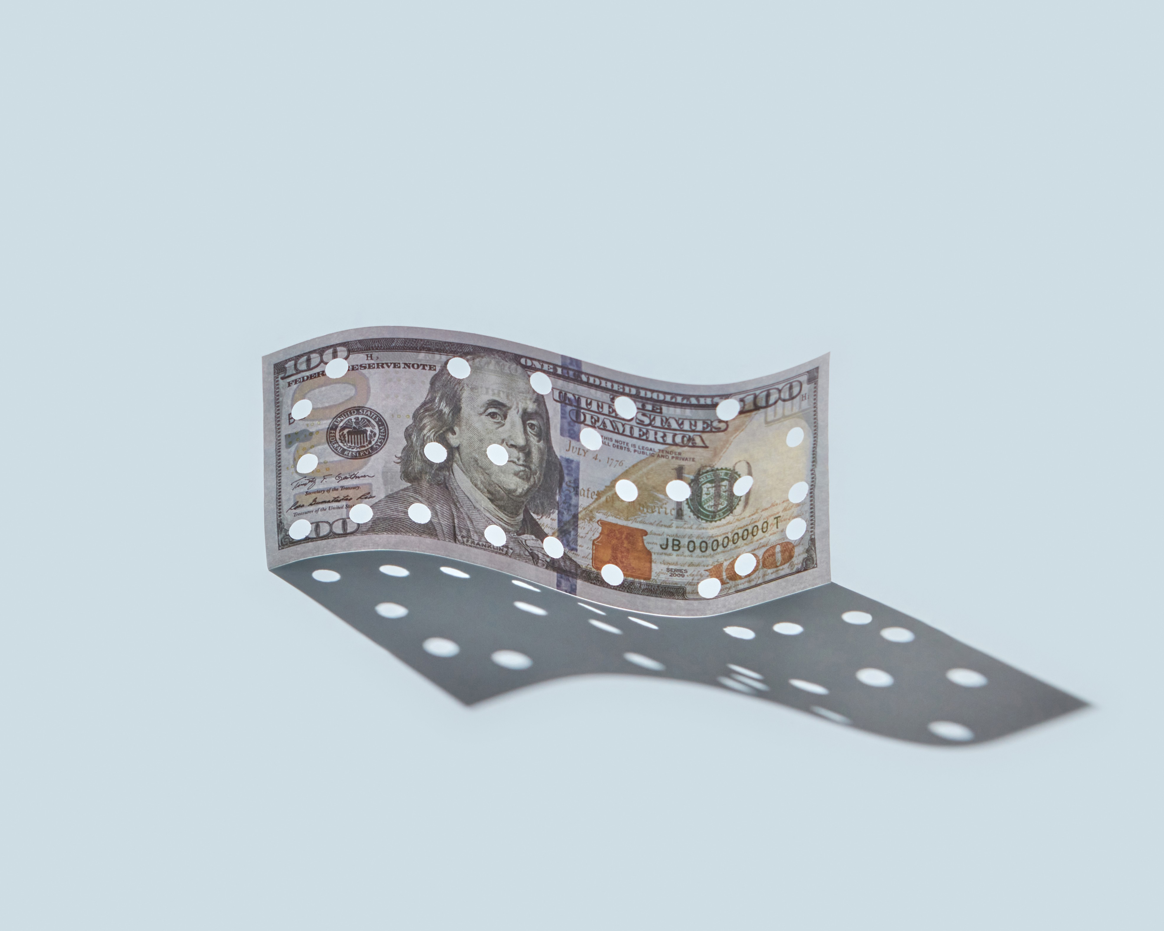 $100 bill with a bunch of holes which creates a sense of unease
